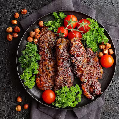 A plate of meat cooked with smoked paprika, with vegetables around it