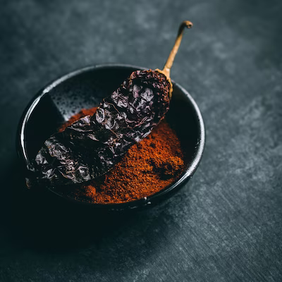 Smoked red pepper on smoked powdered paprika inside a black ceramic plate
